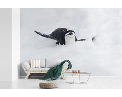 Behang - Fotobehang Een pinguïn glijdt op zijn buik door de sneeuw - Breedte 450 cm x hoogte 300 cm