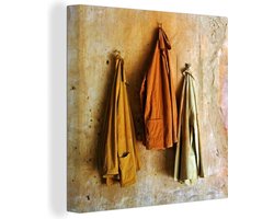 Canvas Schilderij Jassen aan een okergele muur - 90x90 cm - Wanddecoratie